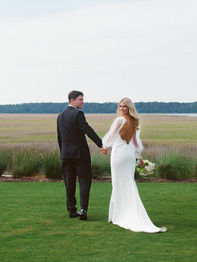 Wedding couple holding hands, bride in white dress looking back