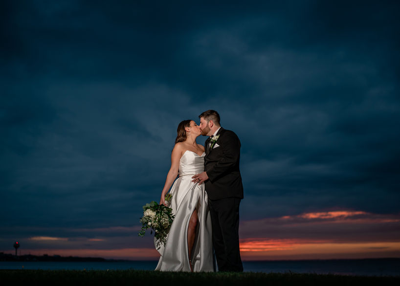 Bride and groom kissing at sunset by the ocean