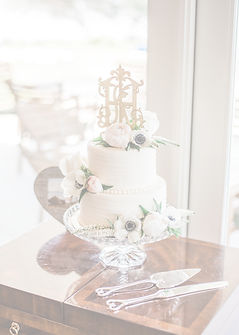 Two-tier white wedding cake with flowers and monogram topper