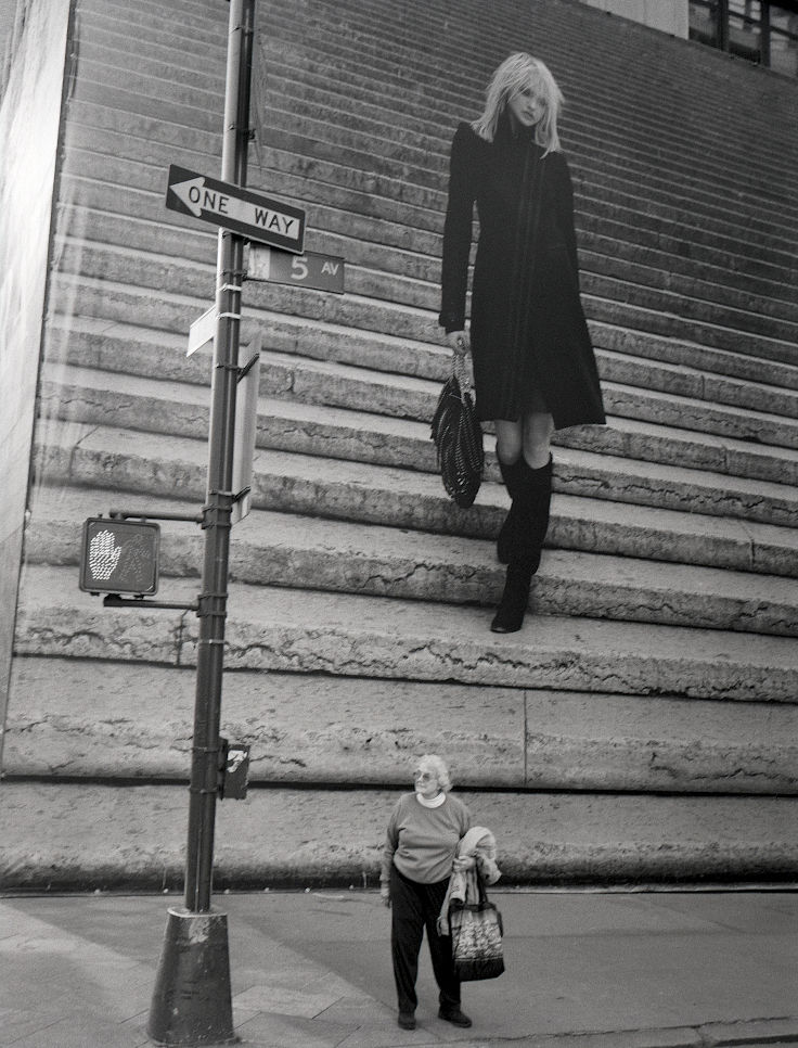 photographie argentique en noir et blanc, vintage 2008. Sur la 5 th avenue de New York, une dame veut traverser au feu tricolore. Derrière elle une immense affiche d'un top modèle descendant des escaliers semble vouloir l'écraser. Obama 2008
