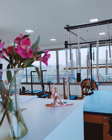 Uma vista do Estudio Pilates Fernanda Moura, com flores e a estatua em movimento de alongamento.