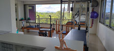 Uma vista ampla do Estudio Pilates Fernanda Moura, com flores e a estatua em movimento de alongamento.