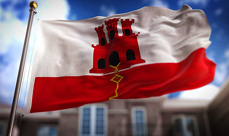 A waving flag of Gibraltar with blue skies in the background
