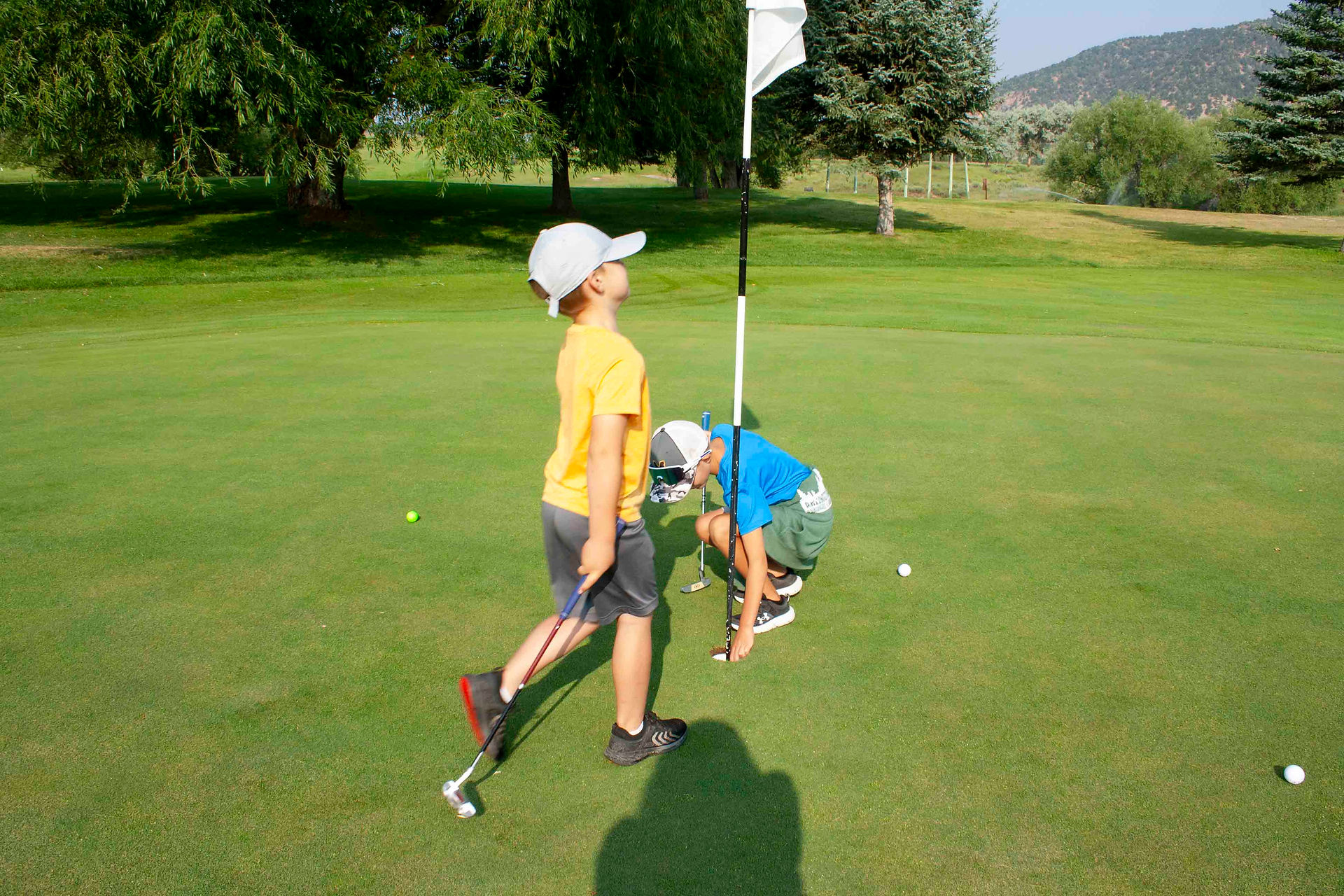 Two boys golfing on putting green