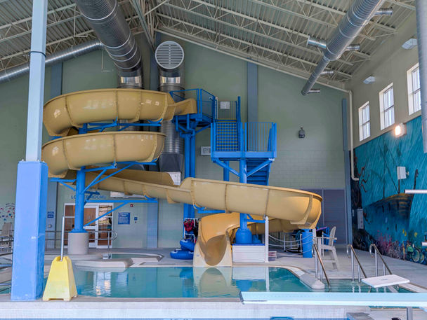 Indoor pool with a spiral water slide and diving board at Meeker Rec Center.