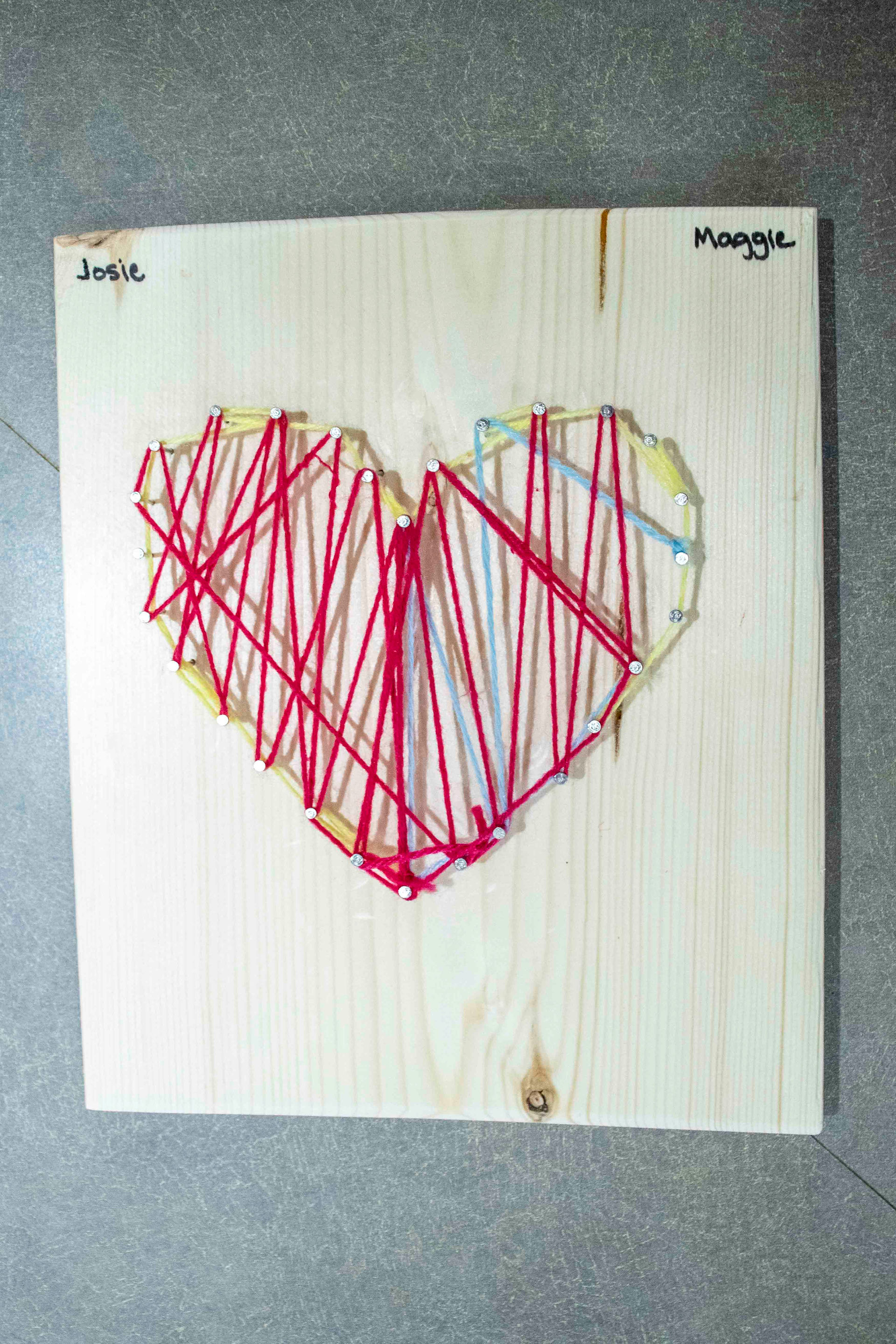 Red, pink, yellow, and a little blue string art in the shape of a heart.
