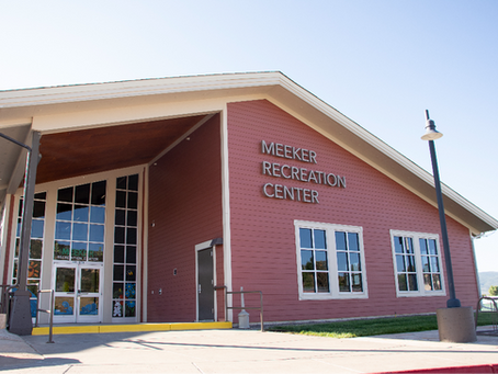 Red building with large windows and "Meeker Recreation Center" text. Bright, sunny day with a clear sky and surrounding greenery.