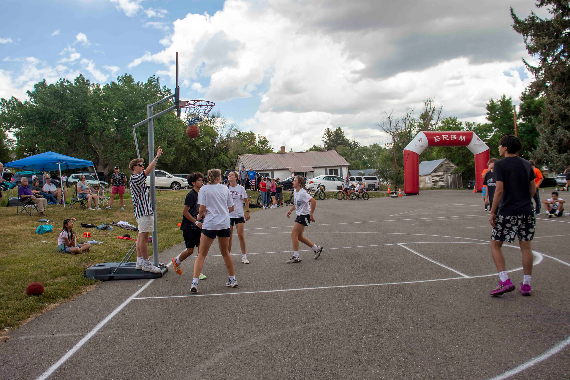 A basketball swishes through a net as several players watch.