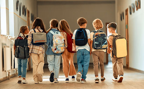 Back to school. A group of schoolchildren with backpacks walk along the school corridor du