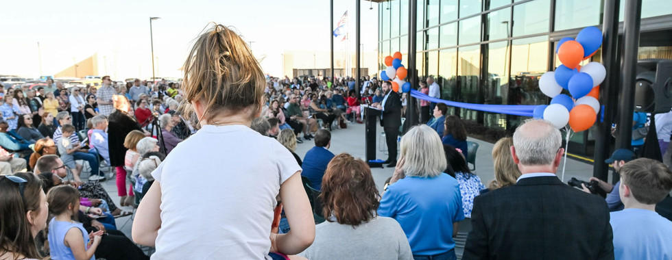 A crowd celebrates the grand opening of the Cabarrus County Library & Active Living Center, marked by speeches, balloons, and a ribbon-cutting.
