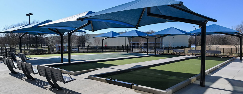 Outdoor bocce and shuffleboard courts with sleek blue canopy shades and seating, creating an inviting recreational space at Afton Ridge Library & Active Living Center.