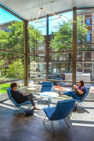 Interior designers Tiffany and Mackenzie enjoying a coffee at the cafe in Kanawha County Public Library, Main Library. The cafe offers modern, floor-to-ceiling windows and comfortable lounge seating, allowing you to relax while feeling immersed in the local community.