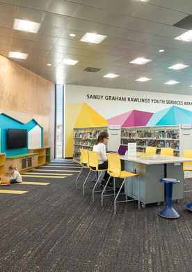 The Sandy Graham Rawlings Youth Services Area blends books, technology, and creative seating into a colorful, engaging space for young learners and families.