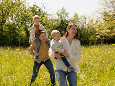 Un couple de parents enlace chaleureusement ses enfants au milieu des rires, photographie de famille naturelle en Alsace.