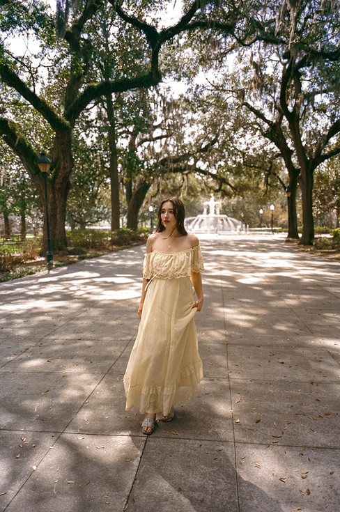 Moody film portrait of bride framed by oak branches and filtered sunlight