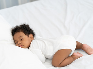 black african american baby sleeping on a white mattress..jpg