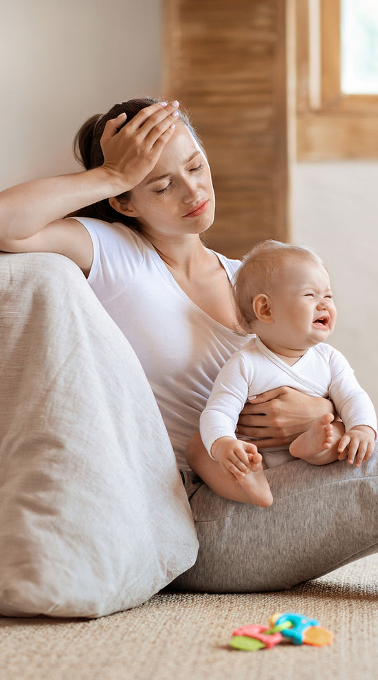 Tired infant baby cries in mother hands, unhappy exhausted mom sitting on floor with cryin
