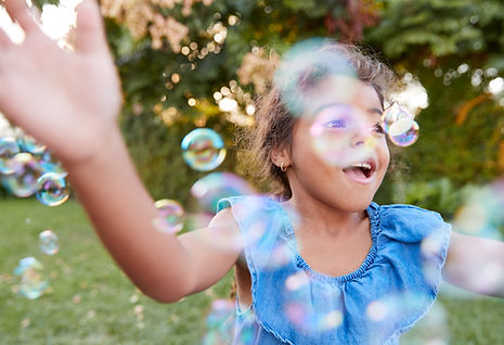 girl-chasing-catching-bubbles-garden