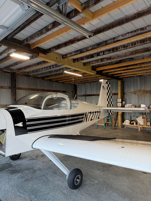 Small aircraft with custom vinyl wrap in a hangar.