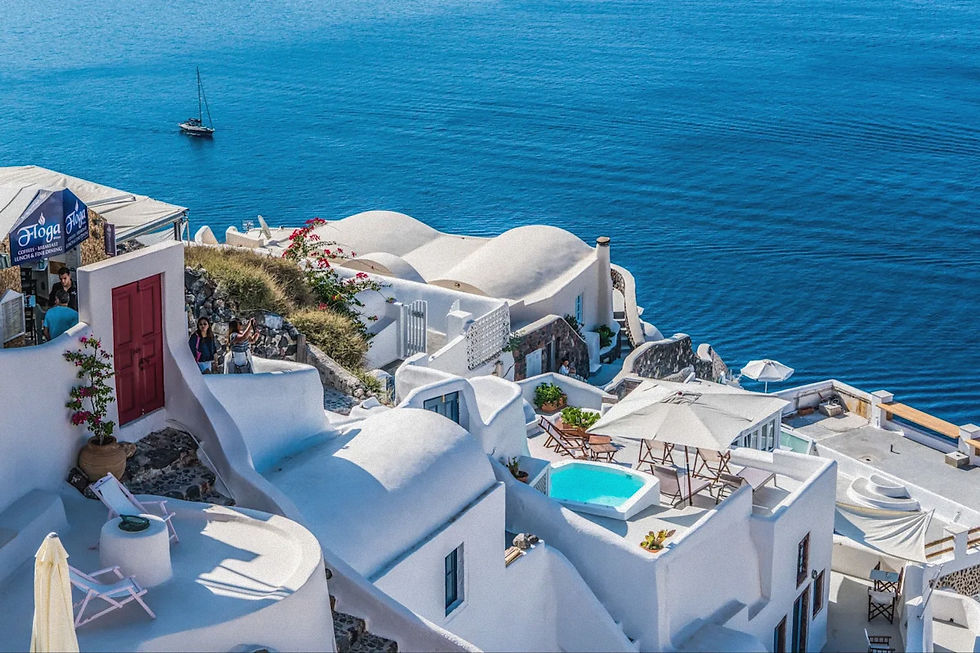 Weiß getünchte Häuser auf Santorini mit Blick auf die Caldera und das tiefblaue Meer an einem sonnigen Sommertag