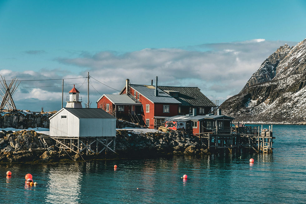 Rote Fischerhäuser am Meer auf den Lofoten vor blauem Himmel
