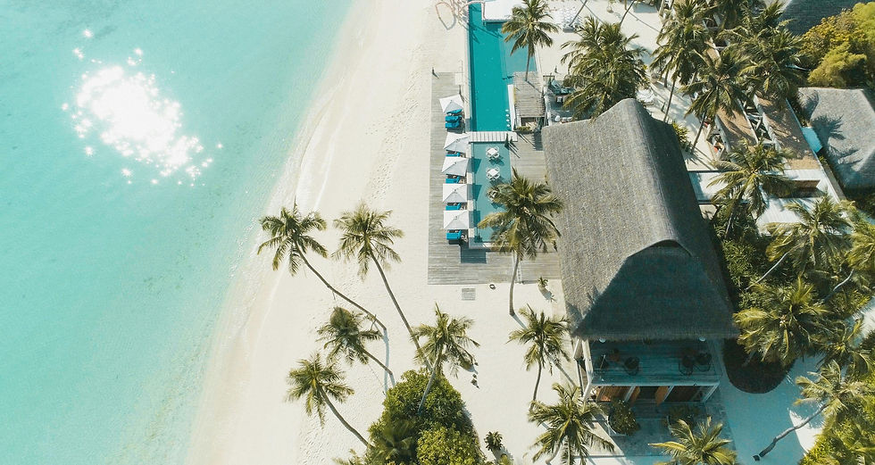 Luftaufnahme eines Resorts auf den Malediven mit Pool direkt am Strand mit türkisem Meer
