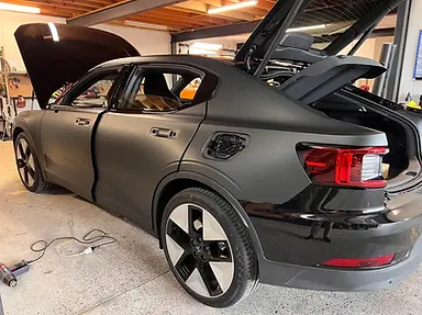A sedan shown in progress of a Matte Finish wrap being applied