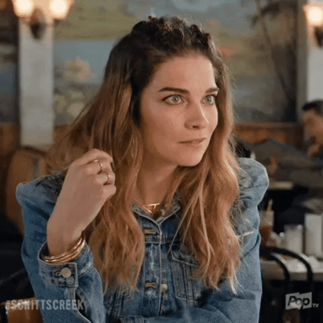 Gif of Alexis Rose (Schitt's Creek character) folding her hands under her chin & leaning forward, as if to say... do tell