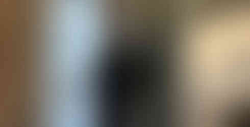 Amanda Wolfson measuring a wall in preparation for hanging artwork in a bedroom with a brick accent wall