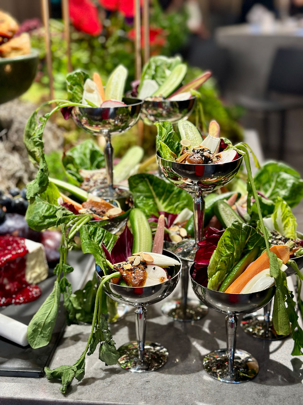 A tiered stand displaying fresh vegetables and fruit, offering a mix of textures and colors, accompanied by small bowls and artful garnishes.