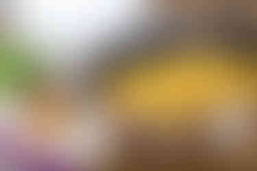 A stovetop pot filled with cheesy macaroni, garnished with parsley, accompanied by a wooden spoon and measuring cups in the background.