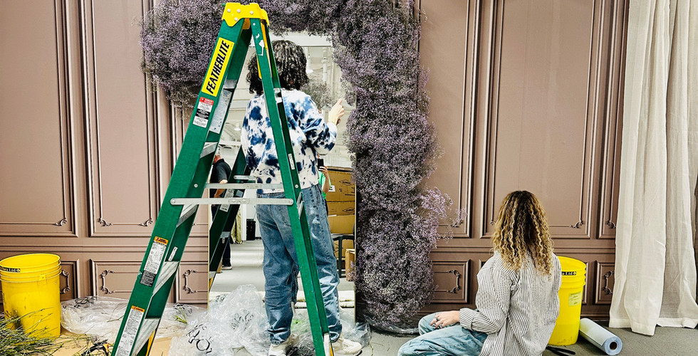 Ladder and team installing purple floral backdrop on paneled display