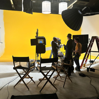 Crew members set up cameras and lighting on a yellow background set for a commercial shoot at Essanay Studios, Chicago.