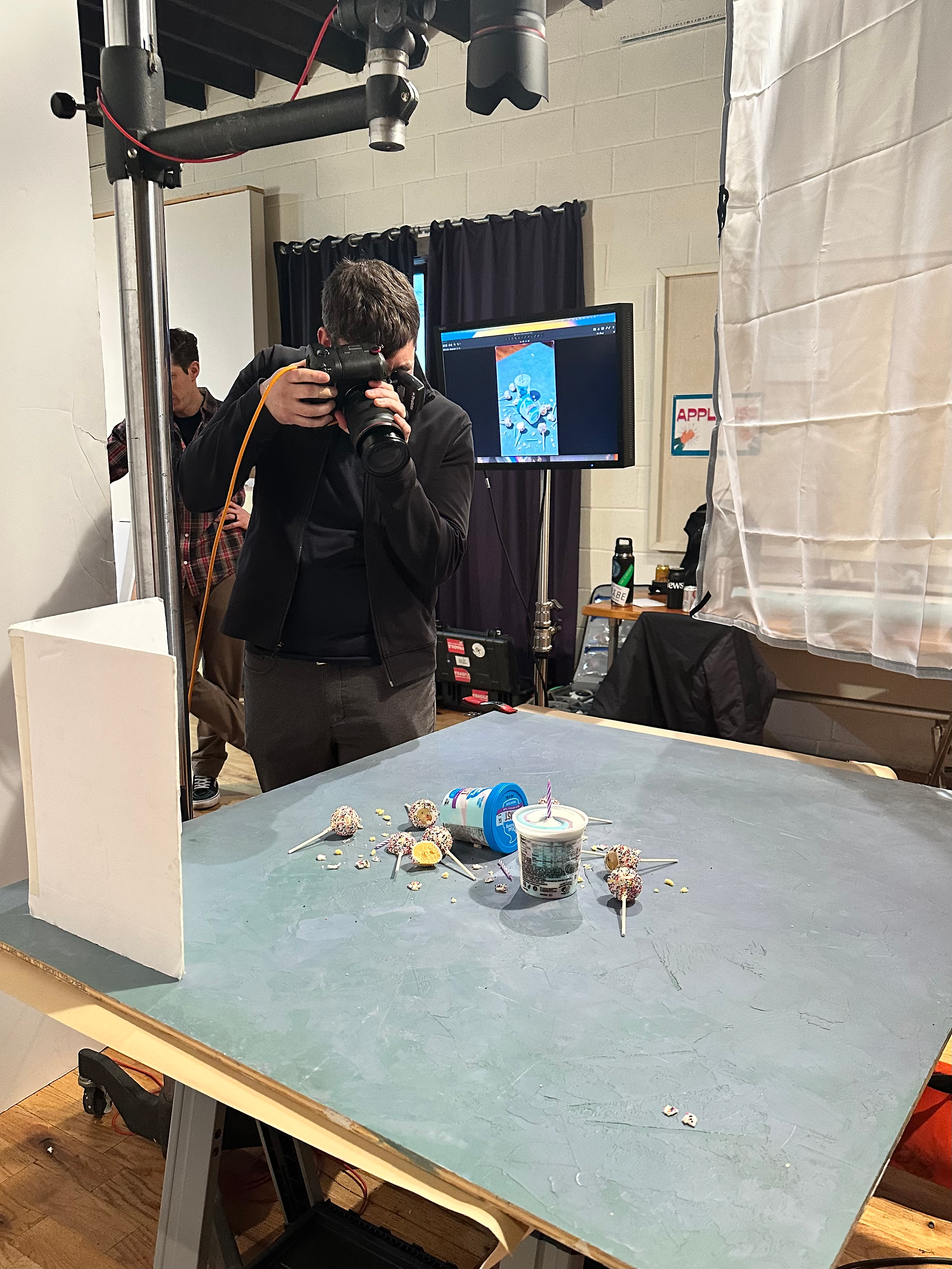 Photographer capturing product shots in a studio setup, with Amanda Wolfson overseeing the styling.