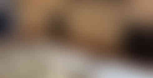 A black metal bed frame partially assembled in a bedroom with a brick accent wall and a light gray area rug.