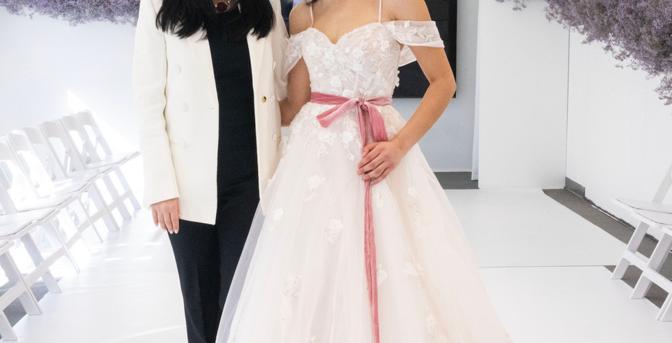 Two models posing in front of Morilee backdrop styled with florals