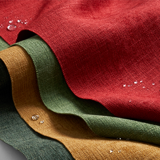 Luxurious red, green, and golden Crypton fabrics layered elegantly, showcasing their water-resistant properties with glistening droplets on the surface.
