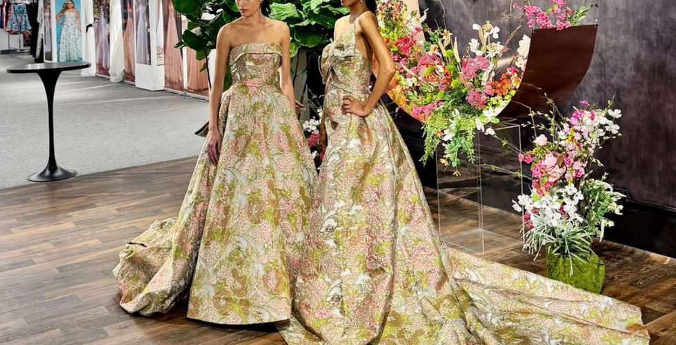 Wide-angle shot of two models in metallic floral gowns posing in front of the completed floral backdrop, highlighting the display’s immersive effect.