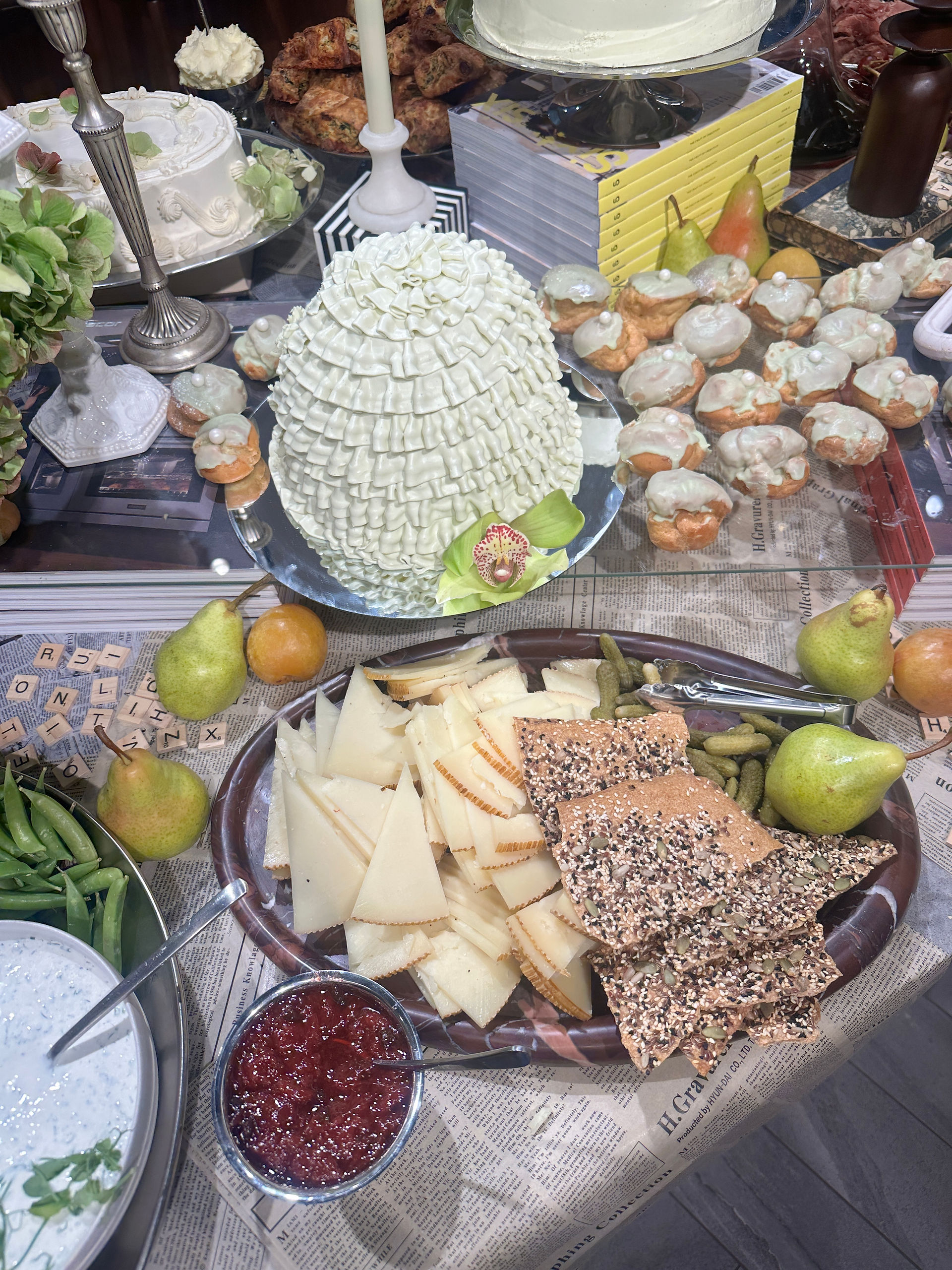Cheese board with pears, grapes, and crackers artfully arranged beside pastries and sculpted butter centerpiece.