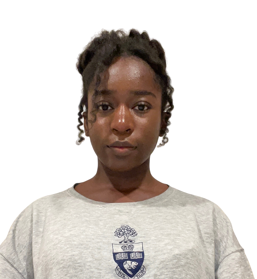 A young woman with dark curly hair styled in a loose updo is facing the camera with a neutral expression. She is wearing a light grey sweatshirt with a navy blue university-style crest on the front. The background is plain white.