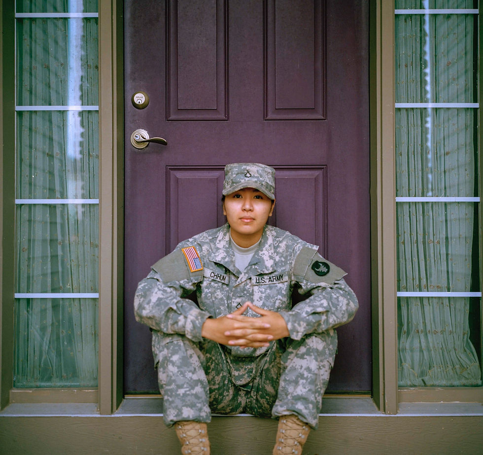 Veteran in uniform proudly sitting in front of a new home, symbolizing successful home buying through VA loans and debt relief opportunities for service members.