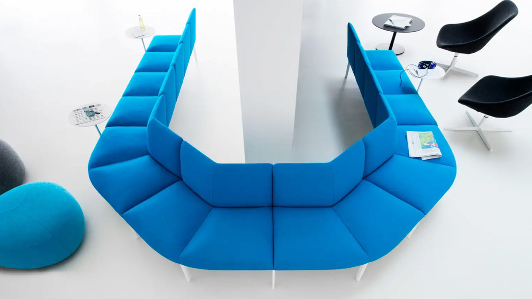 以俯視圖展示了沙發的獨特配置。多個沙發單元圍繞著一張白色長桌，形成了一個半開放的U形討論或休息區。這種設計非常適合辦公室、圖書館或公共空間，能提供一個兼具隱私和社交功能的區域。