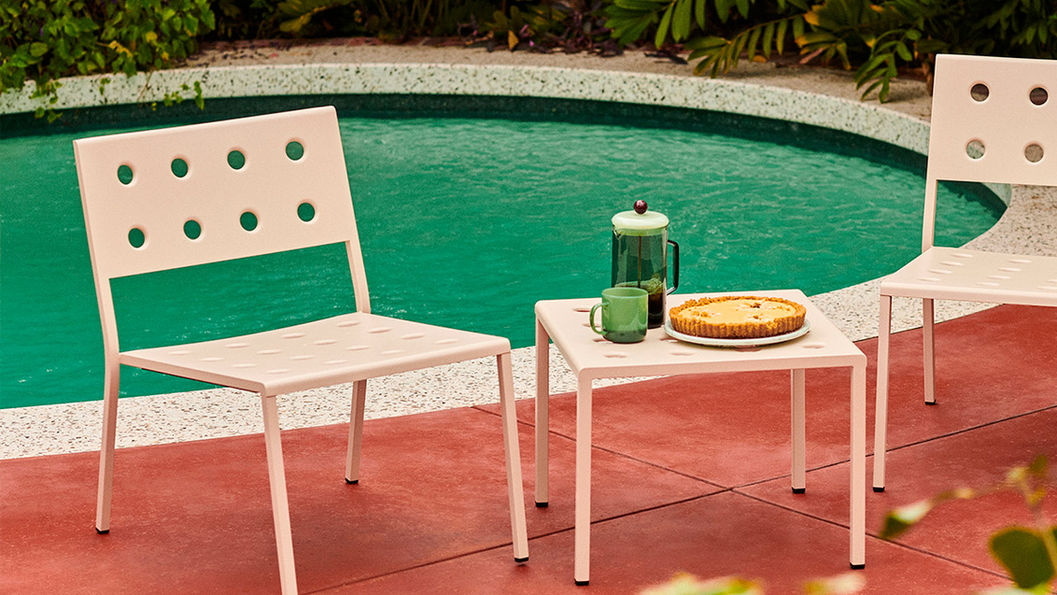 BALCONY 白色椅子和矮桌上有派和咖啡壺,背景是泳池,綠植環繞,氛圍悠閒。