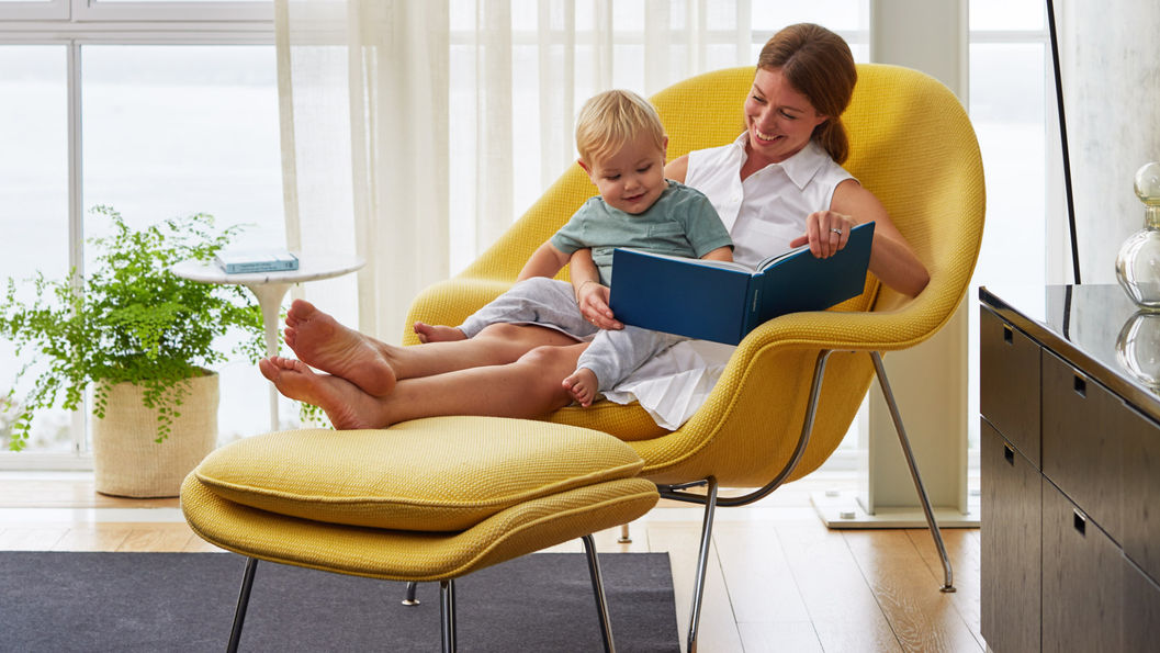 一個媽媽抱著小孩在一張黃色的子宮椅裡舒適的躺著