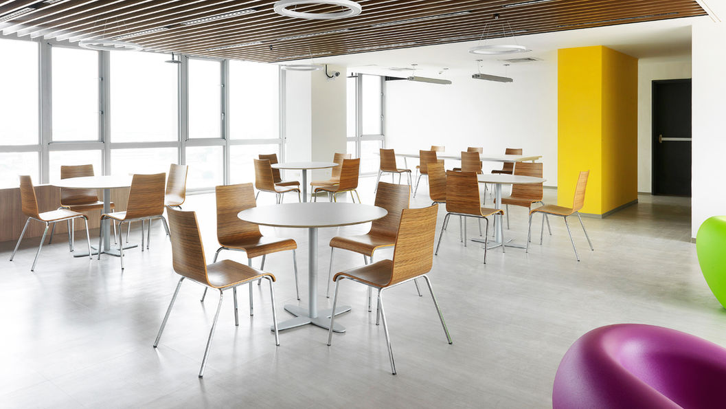 公共空間放置幾張白色圓形桌搭配木頭色椅子