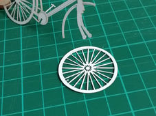 An intricately detailed papercraft bicycle model from "Grains of Recollection," highlighting the craftsmanship by Studio McGuire - Davy and Kristin McGuire.