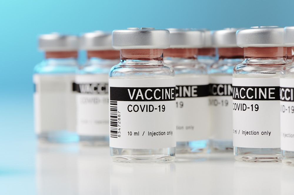 COVID-19 vaccine bottles on a white table with a blue background