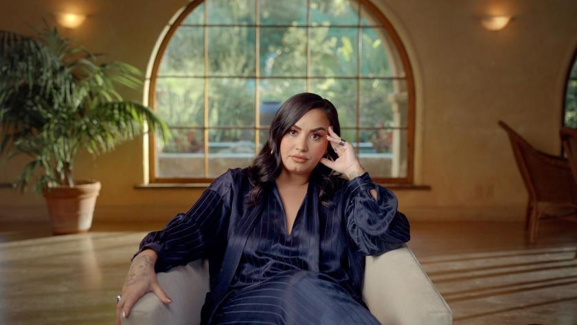Demi Lovato sitting alone in a chair inside