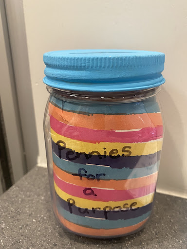 A multi-colored jar with "Pennies for a purpose" written on the front