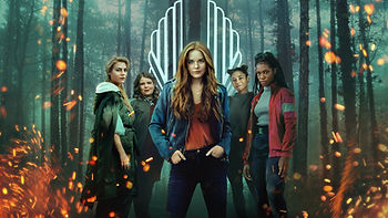 The cover image of Fate: The Winx Saga, featuring five girls in the woods with fire around the edges of the photo